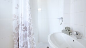 Un baño con ducha, lavabo y toalla.
