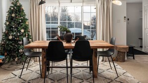 A dining area with a wooden table, black chairs, a Christmas tree, and a large window with curtains. - Halte MB2 — Terrace, Pool, Lake & Hiking (Mont-Blanc)