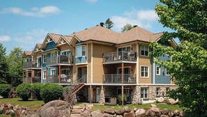 A multi-story building with balconies, a stone foundation, and a staircase leading to the entrance. - Halte MB2 — Terrace, Pool, Lake & Hiking (Mont-Blanc)