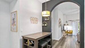Een modern interieur met een houten eettafel, een hanglamp en een gang die naar een andere kamer leidt.