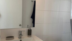 Une salle de bain avec un lavabo blanc, un miroir et des toilettes.