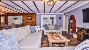 Un salon chaleureux avec un plafond en bois, un ensemble de canapés, une table basse et un téléviseur.