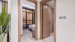 Ein modernes Hotelzimmer mit Bett, einer kleinen Sitzecke und Blick durch eine Glastür.