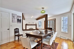 A dining room with a wooden table, chairs, a bowl, and artwork on the walls. - Mountainview Escape 4 Bedroom Home (Killington)