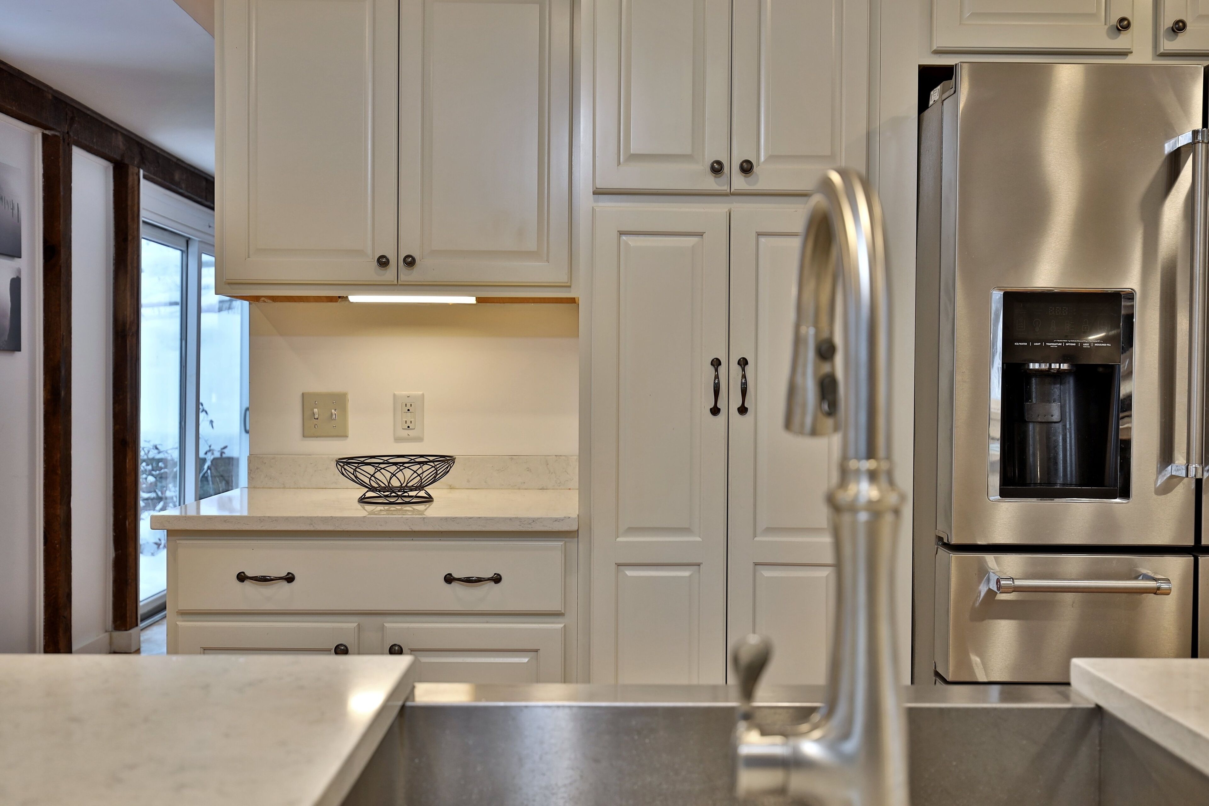 A modern kitchen with white cabinetry, stainless steel appliances, and a marble countertop.