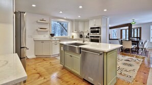 A modern kitchen with white cabinets, stainless steel appliances, and a large island. - Mountainview Escape 4 Bedroom Home (Killington)