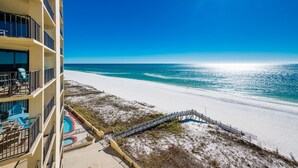 A hotel with a pool, beach view, and a staircase leading to the beach.