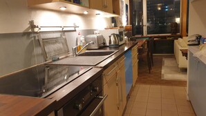 A kitchen with a stainless steel sink, a toaster, and a kettle. There is a window with a view of the city at night.