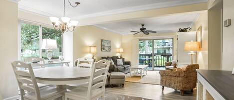 A spacious living room with a dining area, a ceiling fan, and a view of the outdoors.