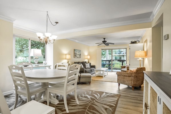 A spacious living room with a dining area, a ceiling fan, and a view of the outdoors.
