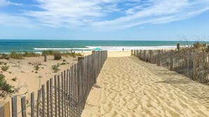 A sandy beach path leading to the ocean, with a wooden fence on one side and a clear blue sky above. - Oceanview Midtown Condo with Pool! SS66500 (Ocean City)