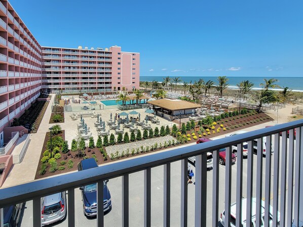 A hotel with a pool, outdoor seating, and a view of the beach.