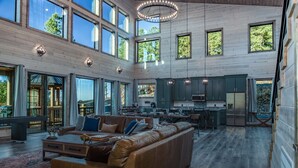 A spacious living area with a large leather sofa, wooden floors, and a kitchen in the background.