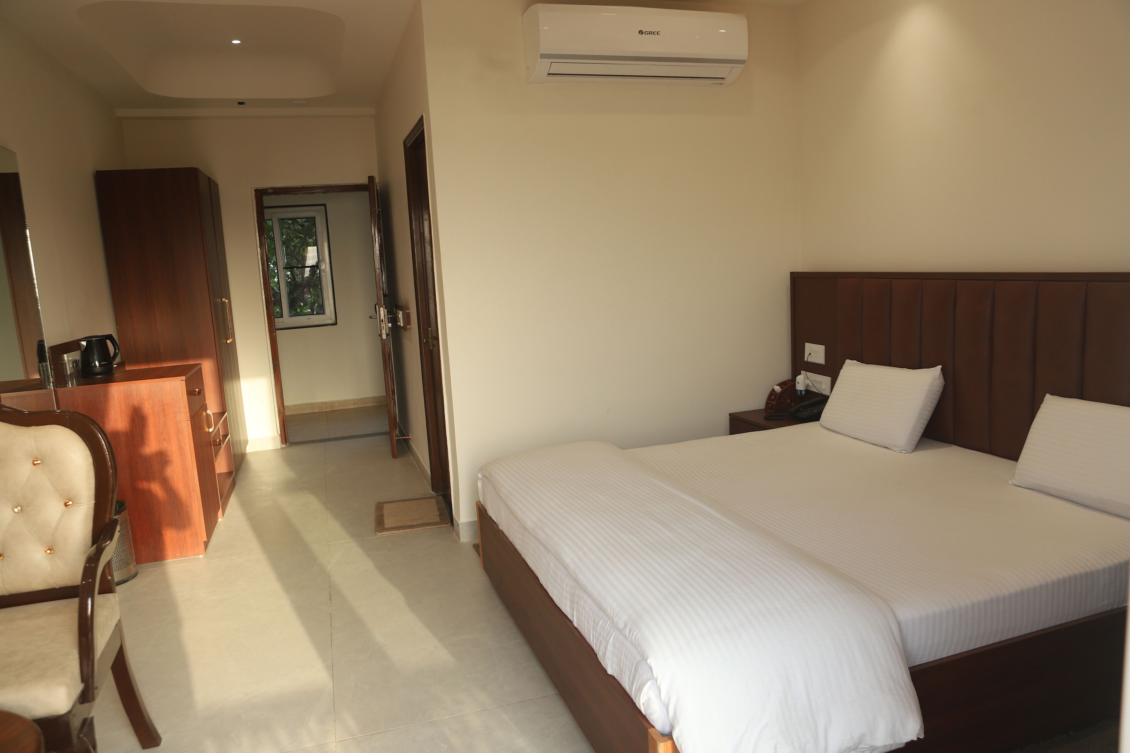Habitación de hotel con una cama grande, un cabecero de madera, un escritorio con una silla y un equipo de aire acondicionado en la pared.
