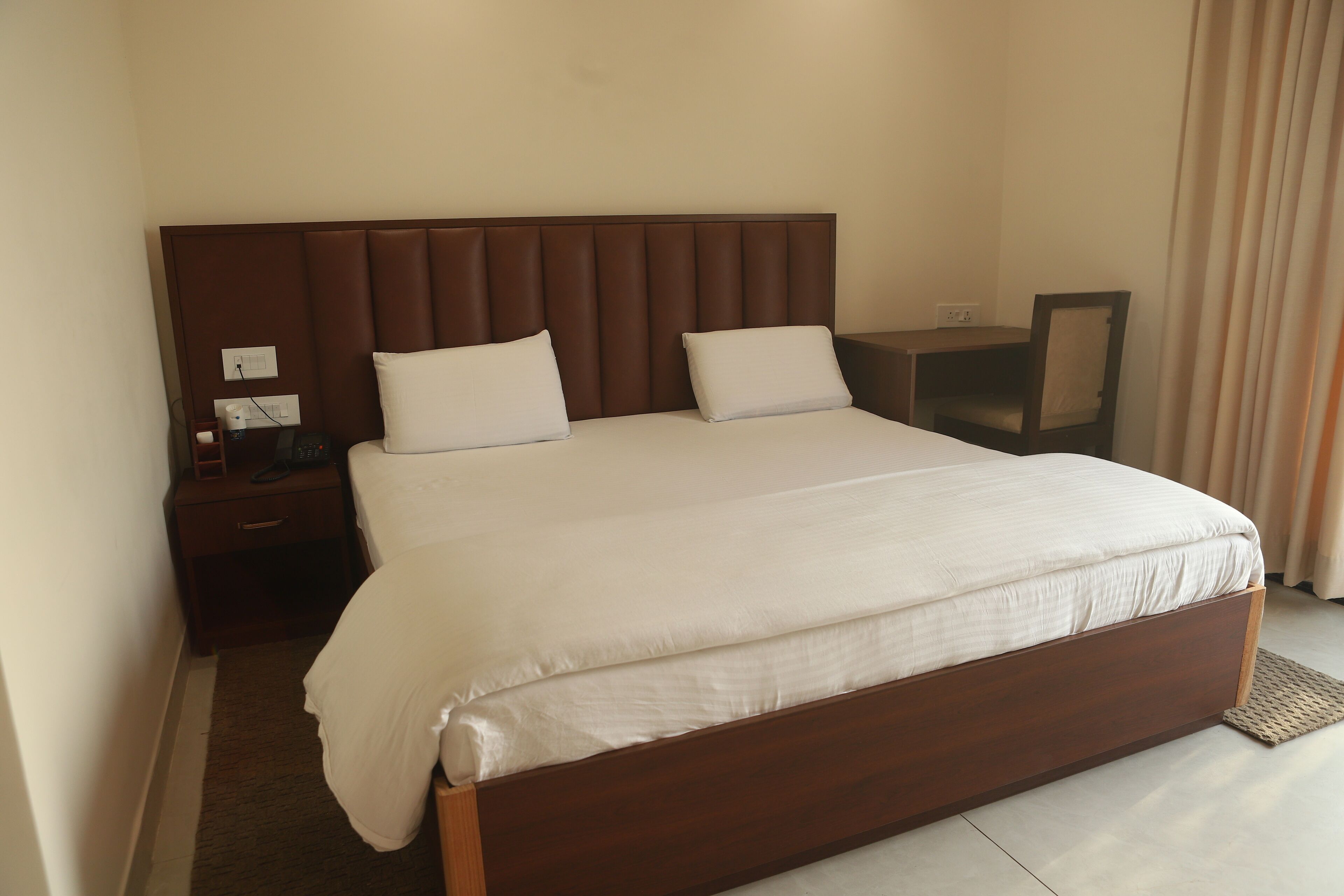 Une chambre d’hôtel avec un grand lit, une table de chevet, un bureau et une chaise.