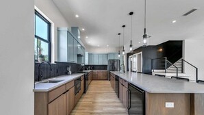 A modern kitchen with wooden cabinets, a central island, and pendant lighting. - Sleeps 30! Private Heated Pool, Hot Tub, Game Room, LSV/Golf Cart, GULF VIEWS! Huge! (Santa Rosa Beach)