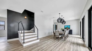 A modern interior with a staircase, dining area, and large windows. - Sleeps 30! Private Heated Pool, Hot Tub, Game Room, LSV/Golf Cart, GULF VIEWS! Huge! (Santa Rosa Beach)
