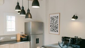 A modern kitchen with a central island, pendant lighting, and a dining area with a wooden table and chairs.