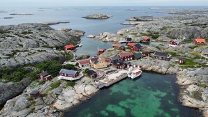A coastal village with red-roofed buildings, a pier, and clear turquoise waters. - Väderöarnas Värdshus (Fjallbacka)