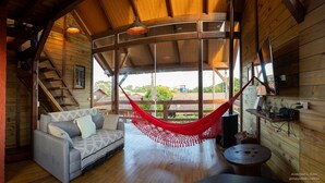 Un interior de madera con una hamaca, un sofá y una escalera.