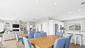 Une cuisine moderne avec des meubles blancs, une table à manger en bois et des chaises bleues.
