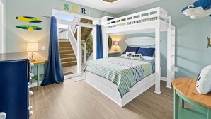 Une chambre avec un lit superposé, un bureau, une chaise et un escalier menant à un espace extérieur.