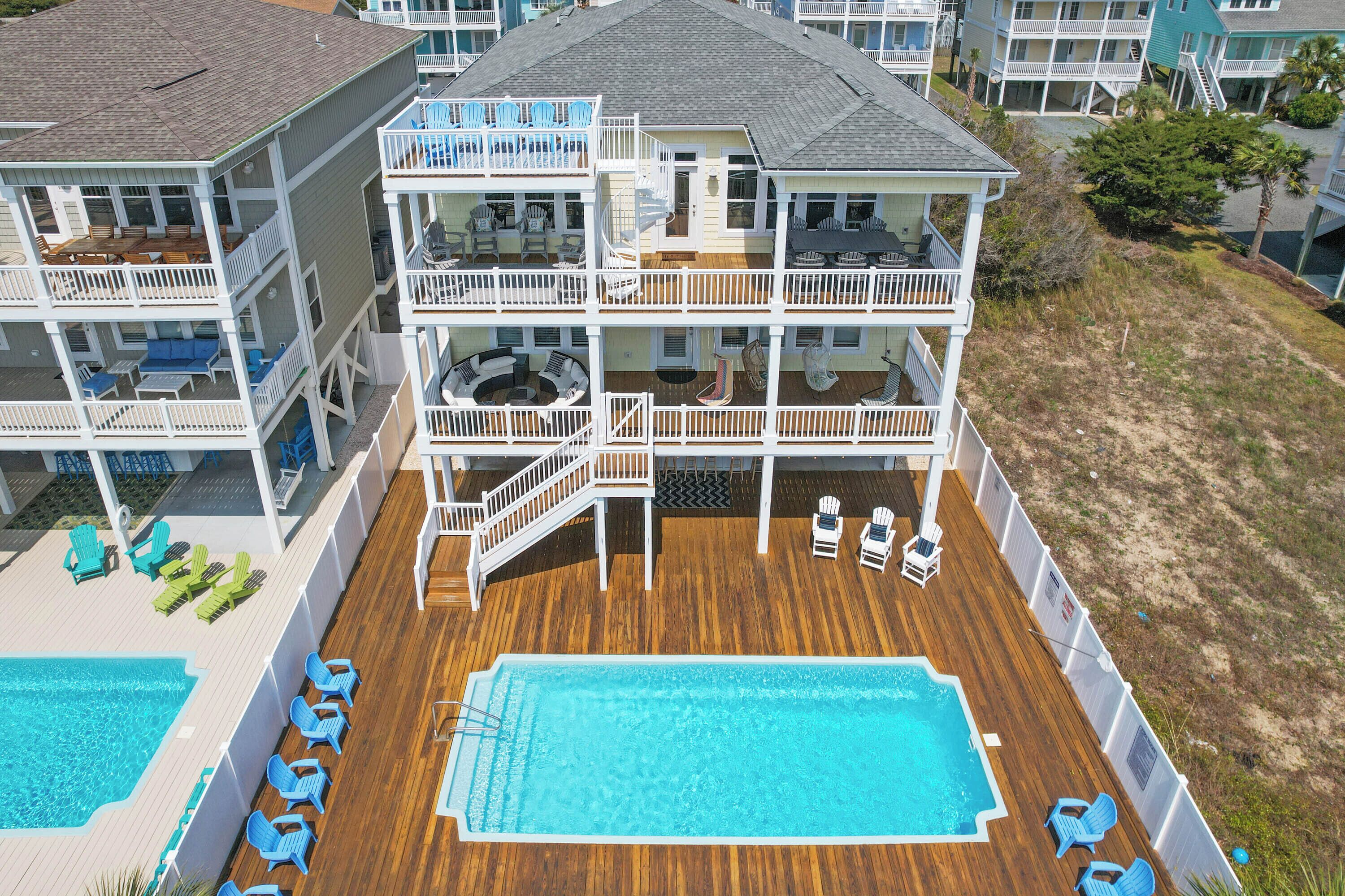 Un hôtel à plusieurs étages doté d’une grande terrasse en bois, d’une piscine et d’espaces de détente en plein air.