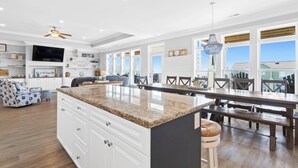 A spacious kitchen with a large island, white cabinetry, and a dining area with wooden chairs and a bench.