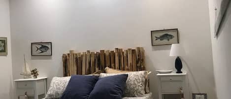 Un dormitorio con cama, mesita de noche, lámpara y aire acondicionado.