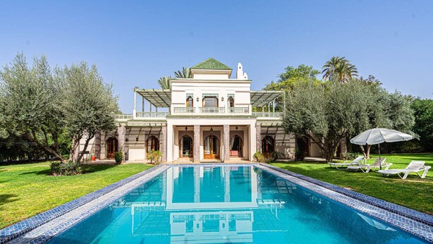 Un grand bâtiment à deux étages, avec une piscine devant.