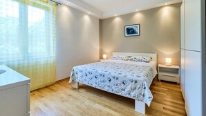 A bedroom with a bed, bedside tables, a nightstand, a window with curtains, and a wall-mounted picture. - Apartment Ady 3 in Mali Lošinj, ideal for two guests. (Mali Losinj)