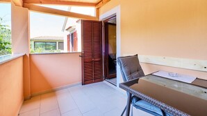 A balcony with a wooden ceiling, a table with a chair, and a sliding door. - Apartment Ady 3 in Mali Lošinj, ideal for two guests. (Mali Losinj)