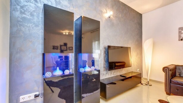 A modern living room with a large flat-screen TV mounted on a textured wall, a glass coffee table, and a leather sofa. - Casa Verde, located in the village Artatore, 150 m distance from the sea, for 5 people. (Cunski)