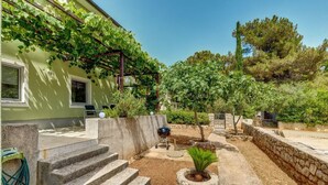 A stone staircase leading to a patio area with a barbecue grill, surrounded by greenery and trees. - Casa Verde, located in the village Artatore, 150 m distance from the sea, for 5 people. (Cunski)
