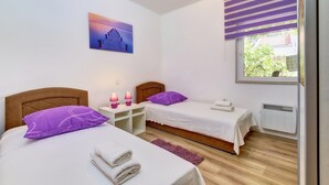 A bedroom with two beds, a window with blinds, a radiator, and a painting on the wall. - Casa Verde, located in the village Artatore, 150 m distance from the sea, for 5 people. (Cunski)