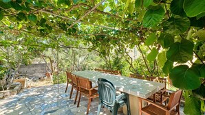 Un área de comedor al aire libre con suelo de baldosas de piedra, una mesa rectangular y sillas de madera.