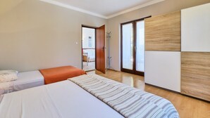 Un dormitorio con dos camas, un armario de madera y una puerta que da a un balcón.