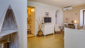 A modern living room with a TV, white furniture, and a decorative vase.