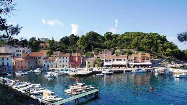 A coastal town with a marina, boats, and buildings along the waterfront.