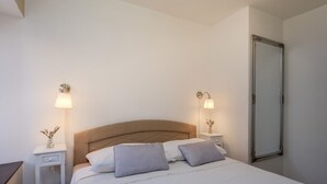 A neatly arranged bedroom with a bed, bedside lamps, a mirror, and a nightstand.