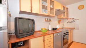 A kitchen with wooden cabinets, a built-in oven, a dishwasher, and a vintage television. - Apartment Orhideja 1 in Mali Lošinj , the nearest beach Zagazinjine is 500 m away. (Mali Losinj)