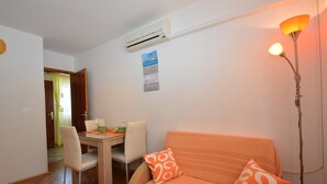 A compact living space with a dining area, a sofa with patterned cushions, and a standing lamp. - Apartment Orhideja 1 in Mali Lošinj , the nearest beach Zagazinjine is 500 m away. (Mali Losinj)