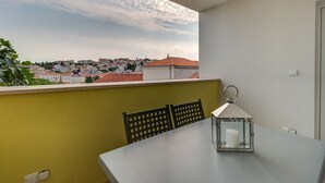 A balcony with a table and chairs, a candle holder, and a view of a cityscape.
