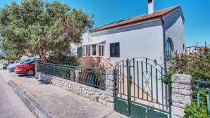 Une maison à deux étages avec un mur en pierre et un portail en métal.