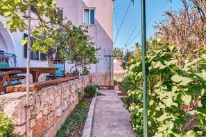 Paret de pedra, un banc de fusta i una taula amb caires davant d'un edifici.
