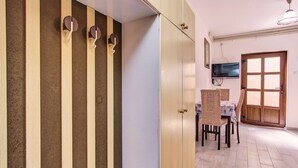 Une chambre dotée d’une armoire, d’un téléviseur fixé au mur et d’un coin repas avec des chaises et une table.
