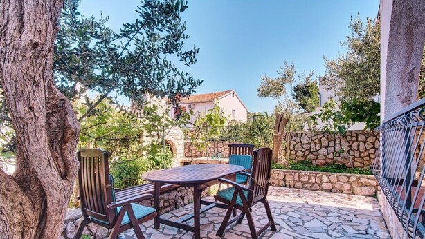 Une terrasse extérieure avec un sol carrelé en pierre, une table ronde et deux chaises.