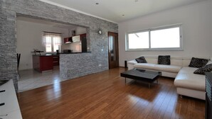 A spacious living area with a stone accent wall, a modern kitchen, and a large window providing natural light.