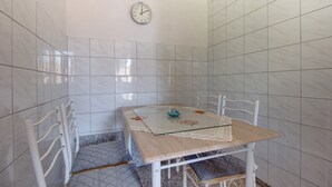A small, tiled bathroom with a glass table, a clock, and a chair. - Two-room apartment Simpatico located in the village of Artatore. (Cunski)