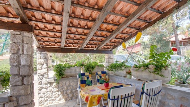An outdoor patio with stone walls, a tiled roof, and potted plants. - Two-room apartment Simpatico located in the village of Artatore. (Cunski)